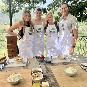 Group of 4 people wearing aprons standing behind an outdoor table