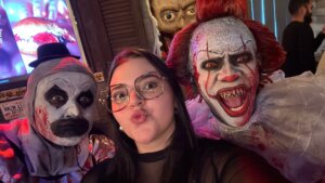 Image of Luiza standing with two people dressed as scary clowns